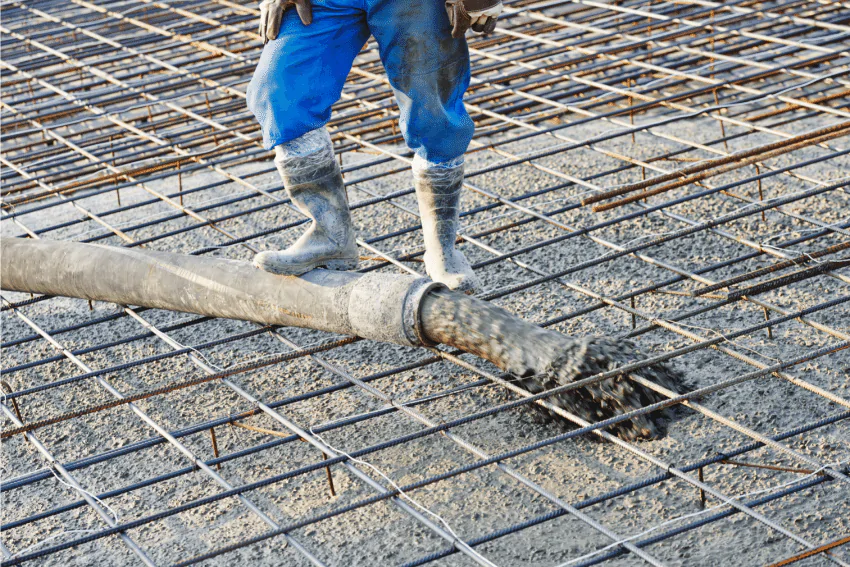 Man pouring concrete into steel frame to make reinforced concrete