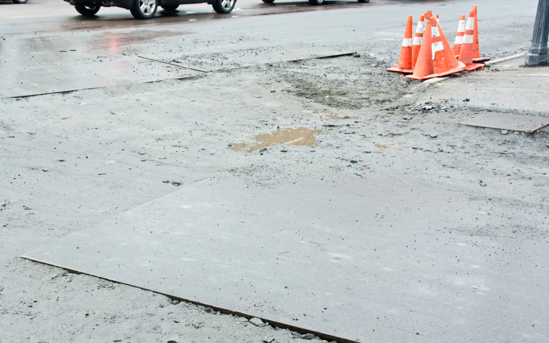 Steel road plates with cars and traffic cones.